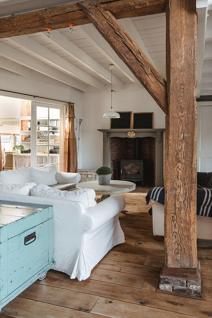 Living room with exposed beams, fireplace and vintage chest in pastel colours