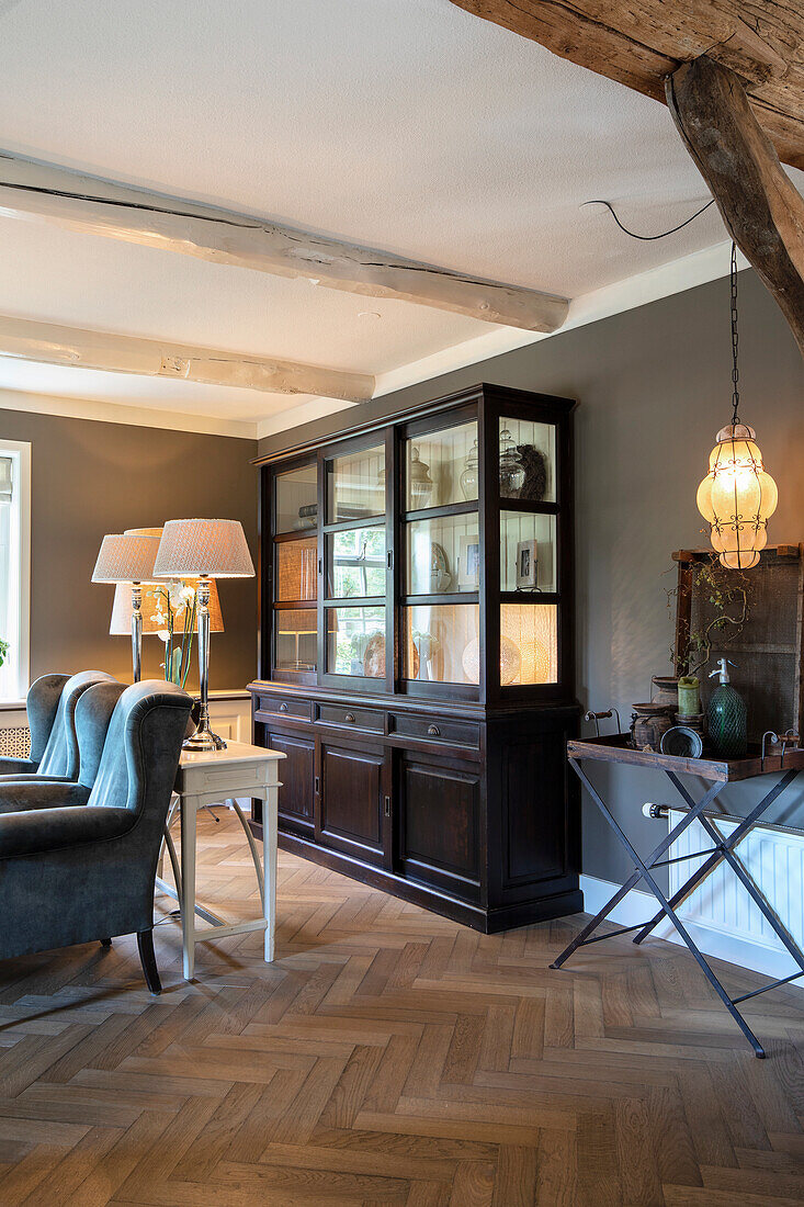 Living room with herringbone parquet flooring and dark display cabinet