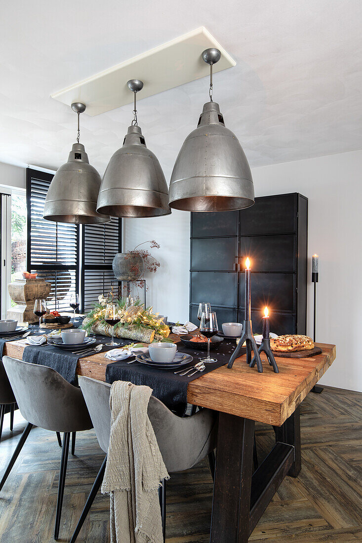 Industrial design dining area with solid wood worktop, velvet chairs and metal lamps