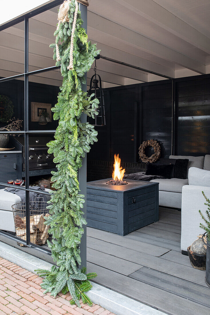 Überdachte Terrasse mit Feuerstelle und hängender Tannengirlande