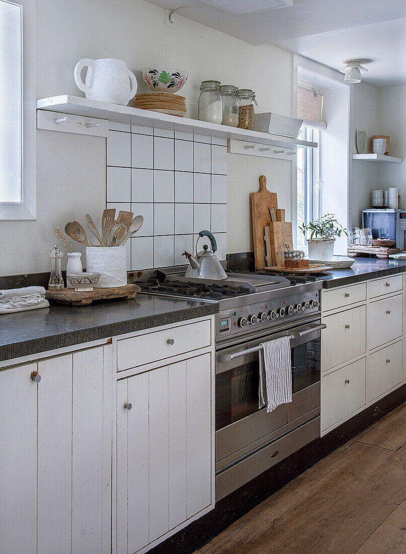 Country kitchen with white cabinets, gas oven and wooden floor