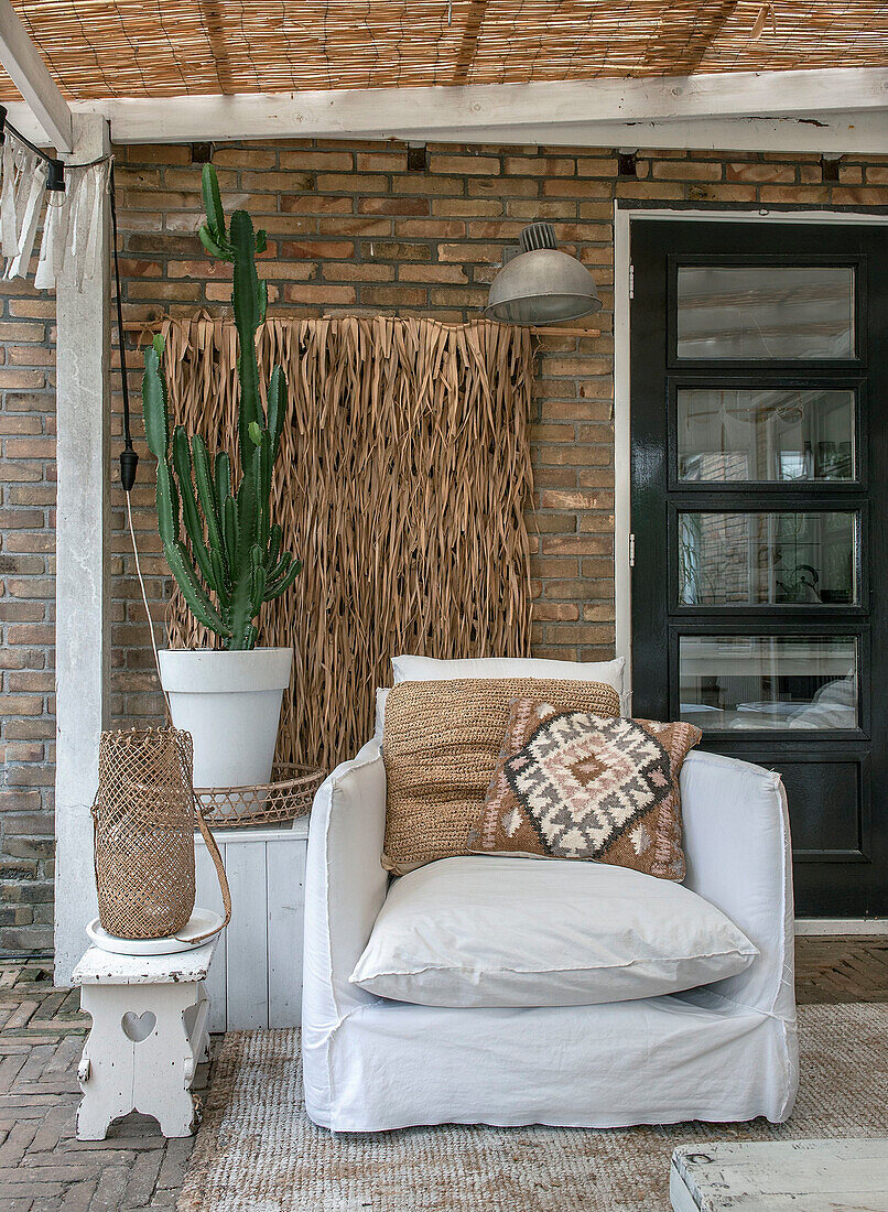 Covered terrace with armchair, cactus and rustic wooden elements