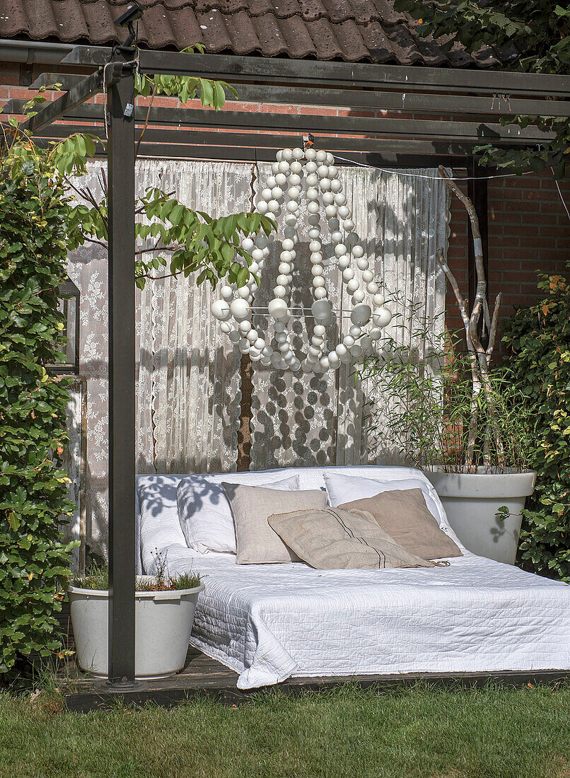 Bed on terrace with pergola and large lamp in the garden