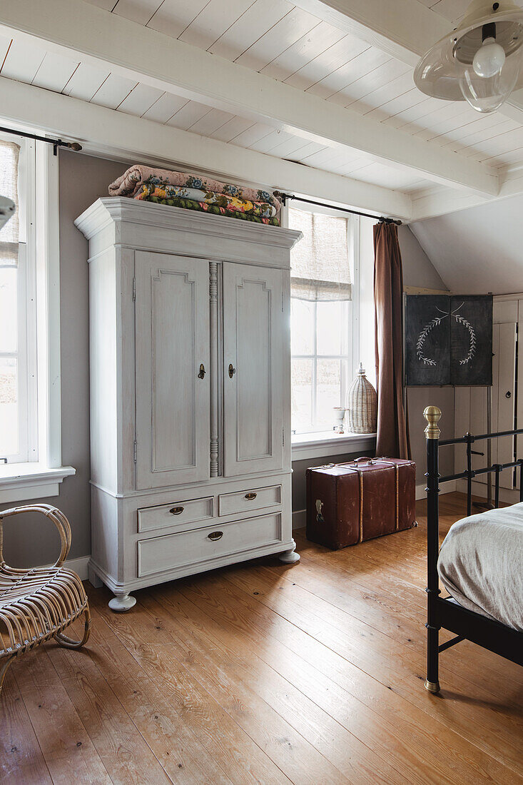 White wardrobe in bedroom with wooden floor and beamed ceiling