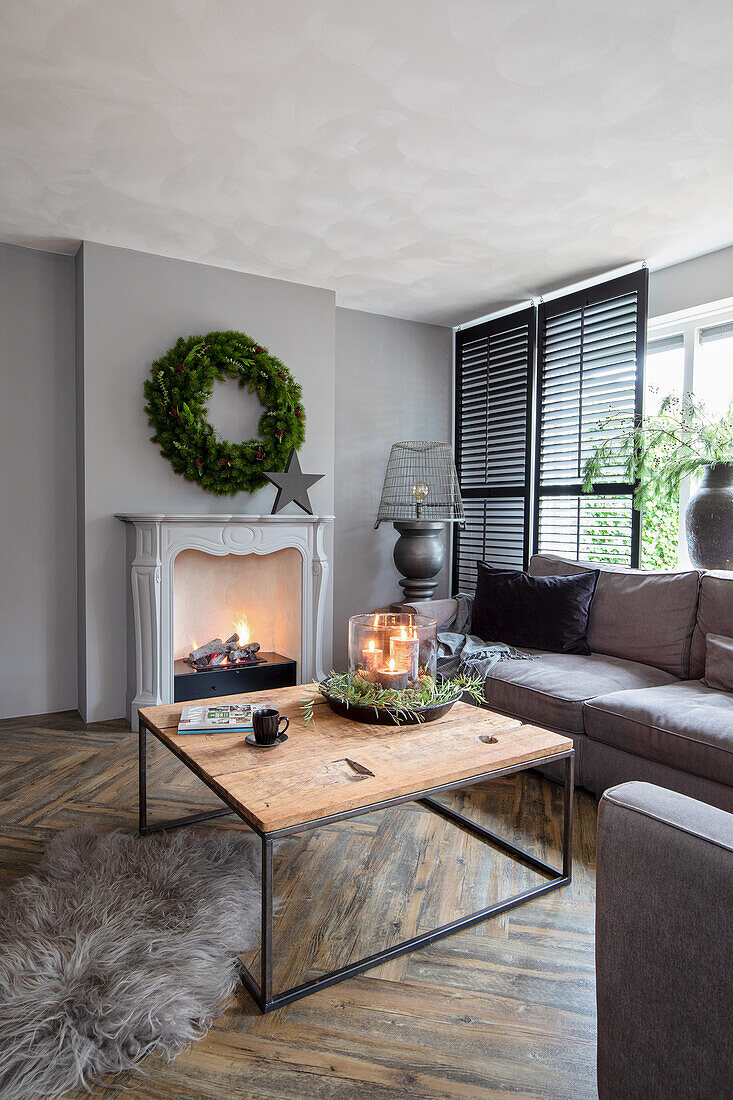 Living room with fireplace, grey corner sofa and wooden table on herringbone parquet flooring