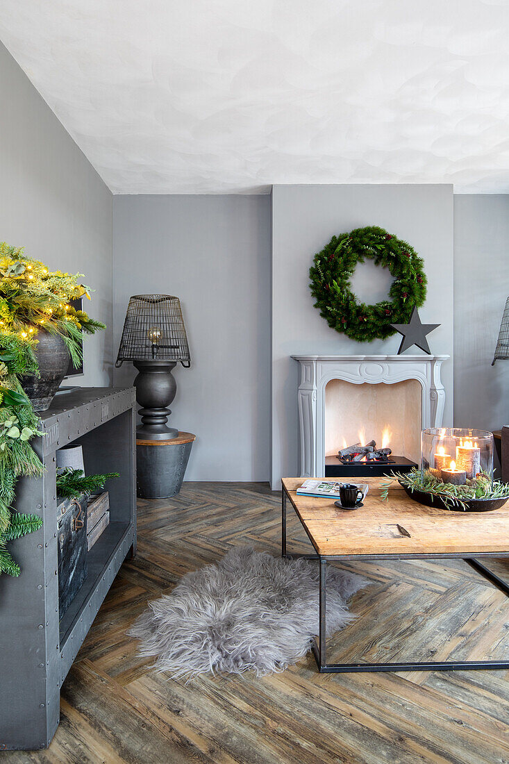 Living room in grey tones with a burning fireplace and Christmas decorations made of fir branches