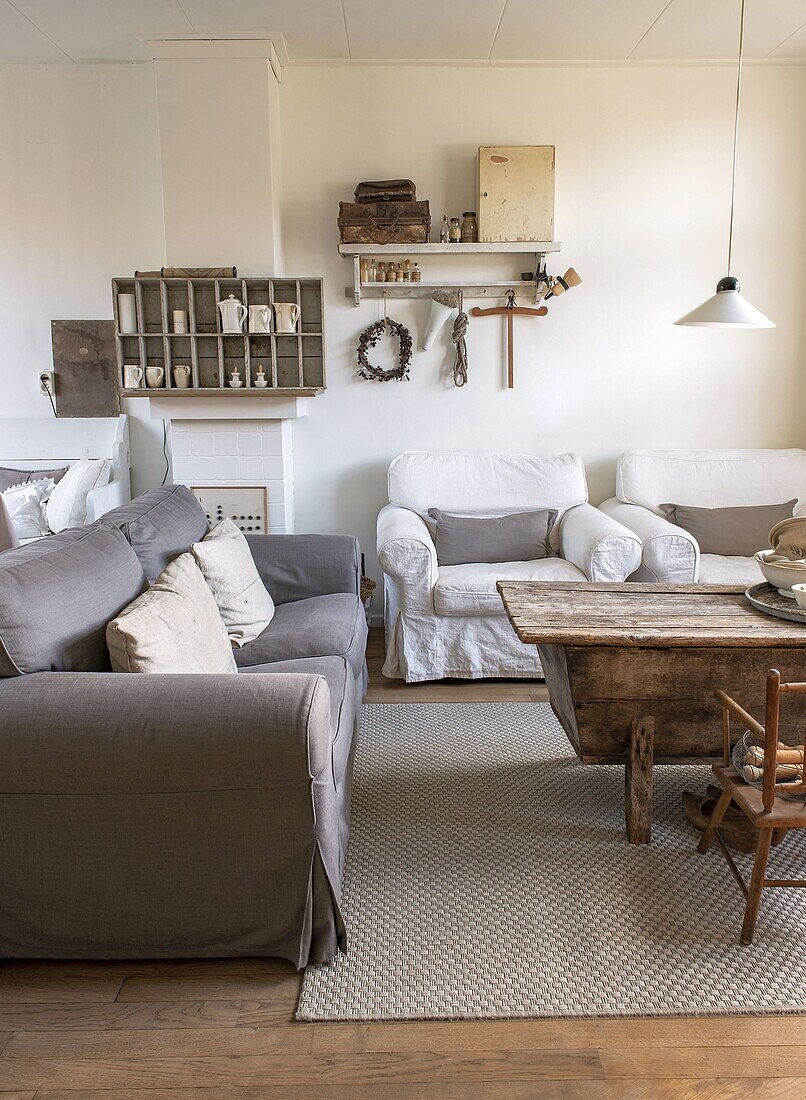 Living room with grey sofa, white armchairs and rustic wooden table