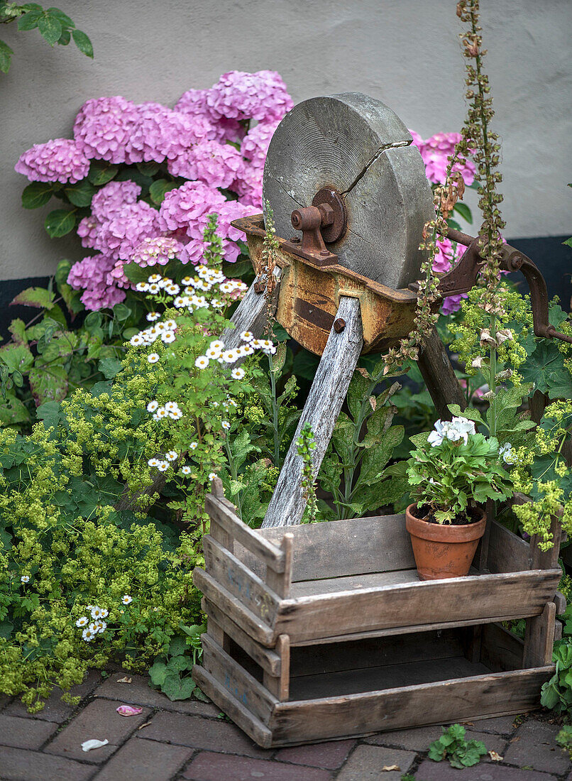 Historic grindstone surrounded by flowers in the garden