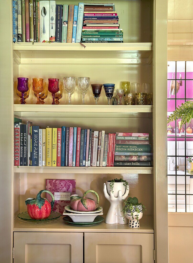 Shelves with books, colorful glasses and decorative ceramics