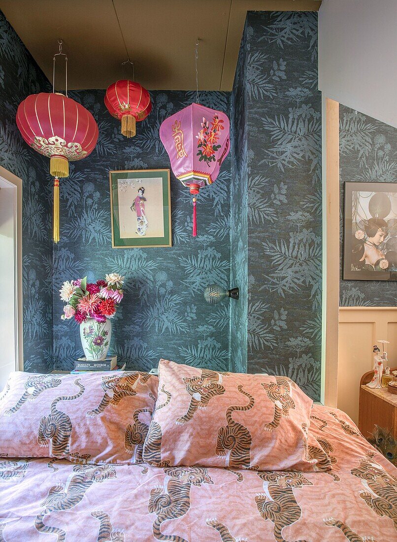 Schlafzimmer mit Tigerbettwäsche, Tapete mit Blättern und Lampions im asiatischen Stil