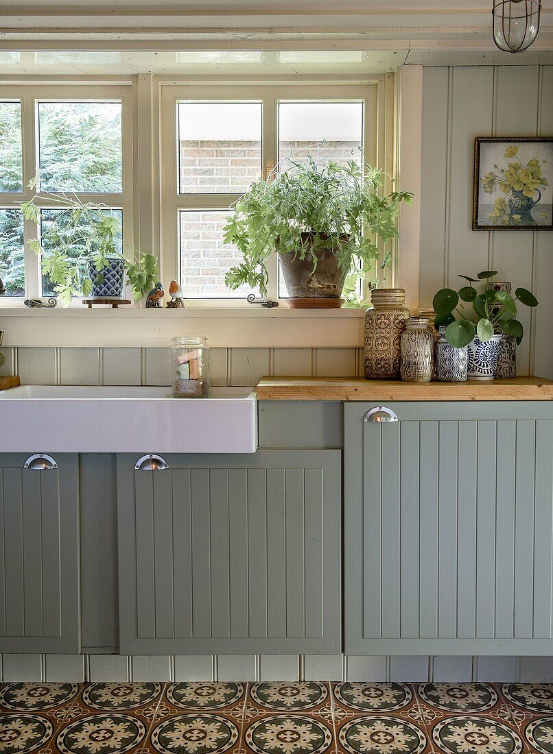 Kitchen with grey-green cupboards and ornamental tiles