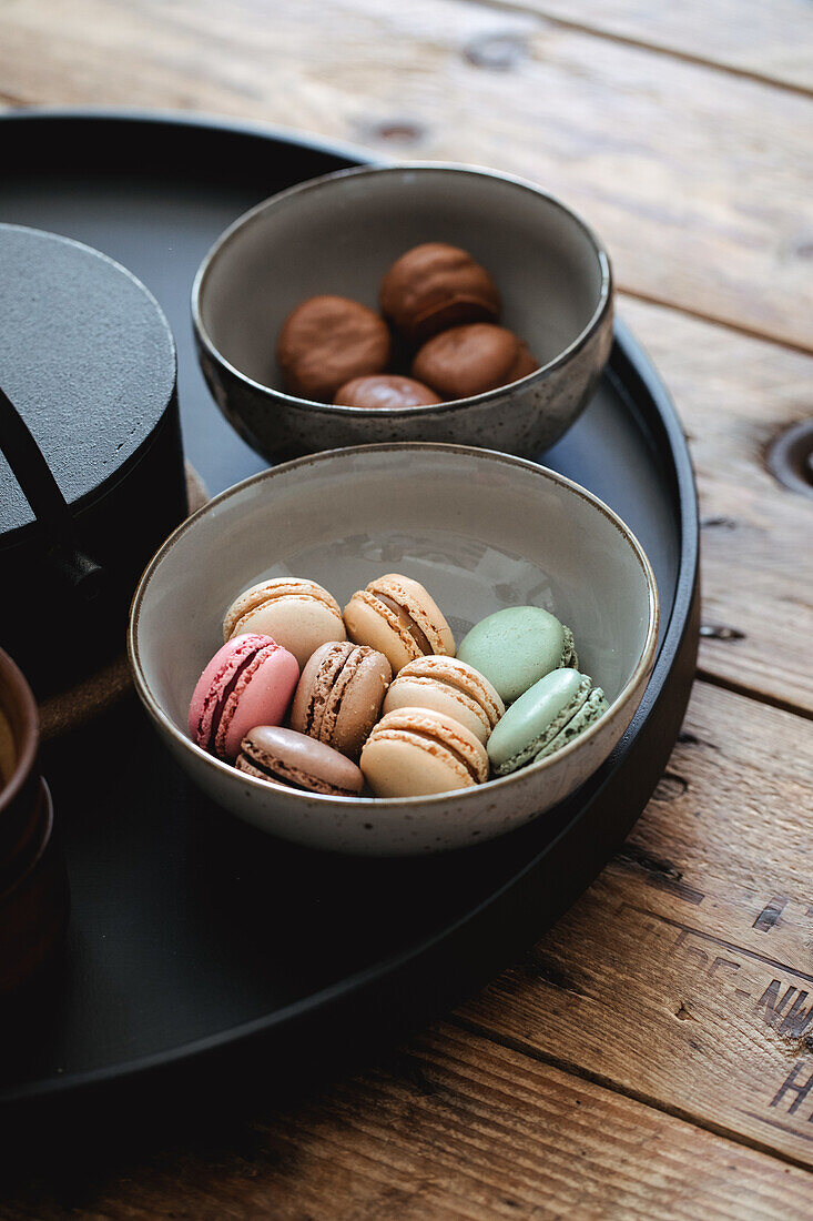 Macarons in Pastellfarben in Keramikschale auf Holztisch