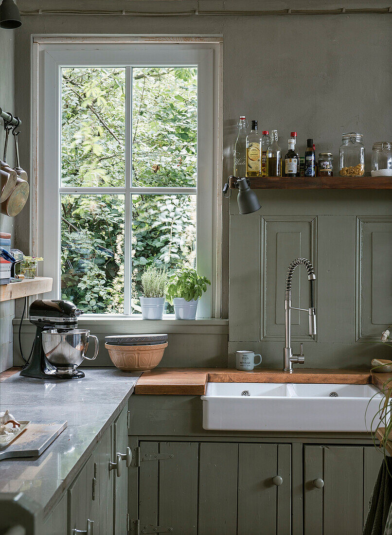 Kitchen with farmhouse sink, wooden worktop and herb pots by the window