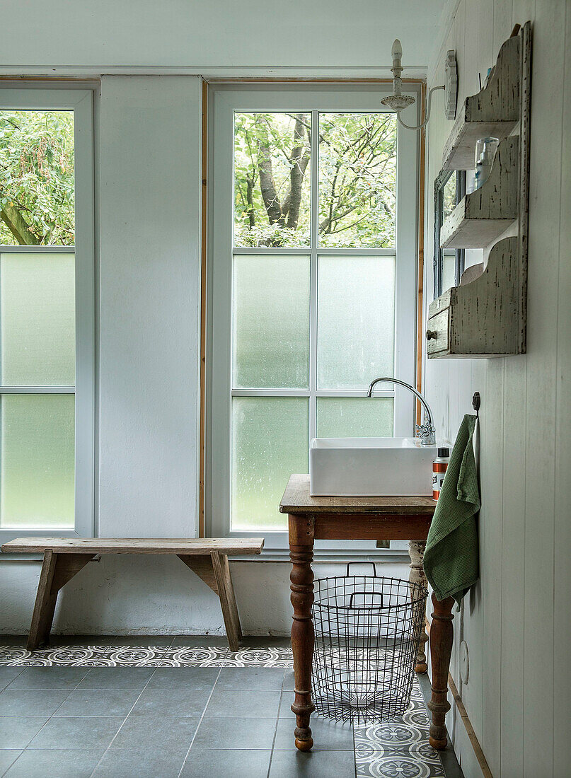 Bathroom with wooden bench, vintage washbasin and windows with privacy screens