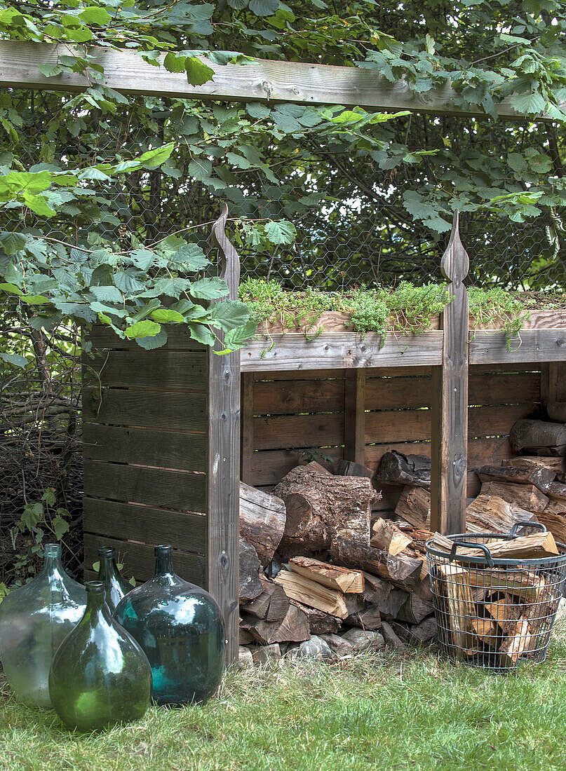 Holzlager, Glasflaschen und Korb im Garten