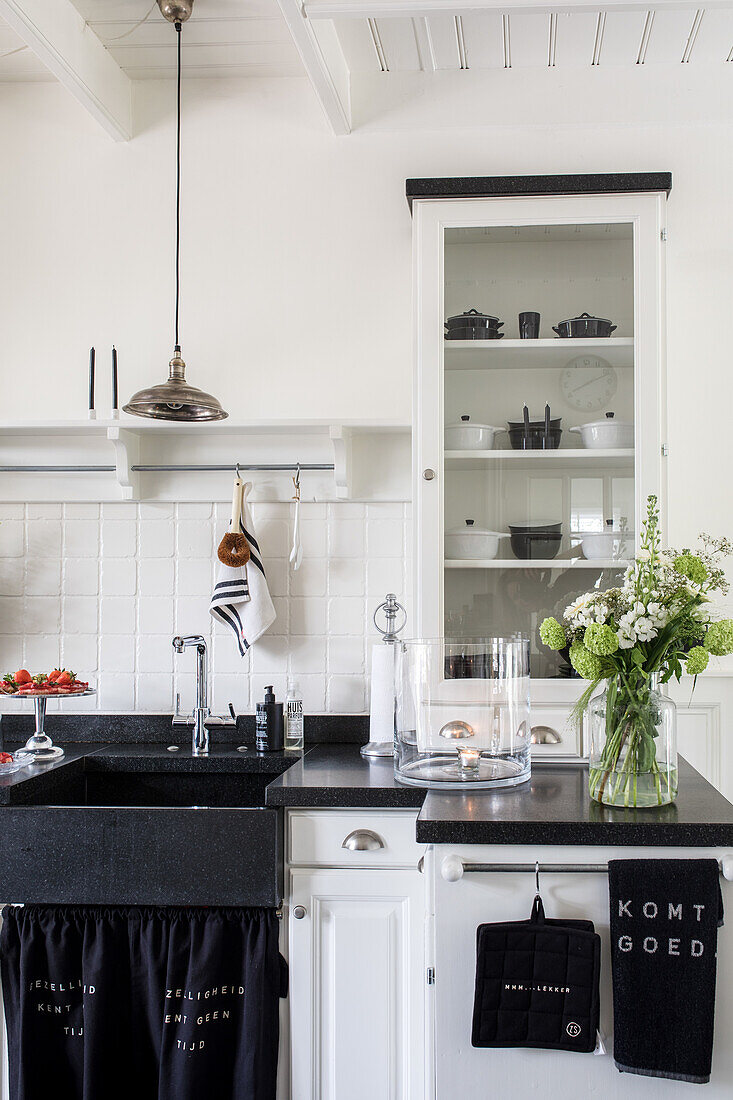 Kitchen in black and white with bouquet of flowers, shelves and large sink