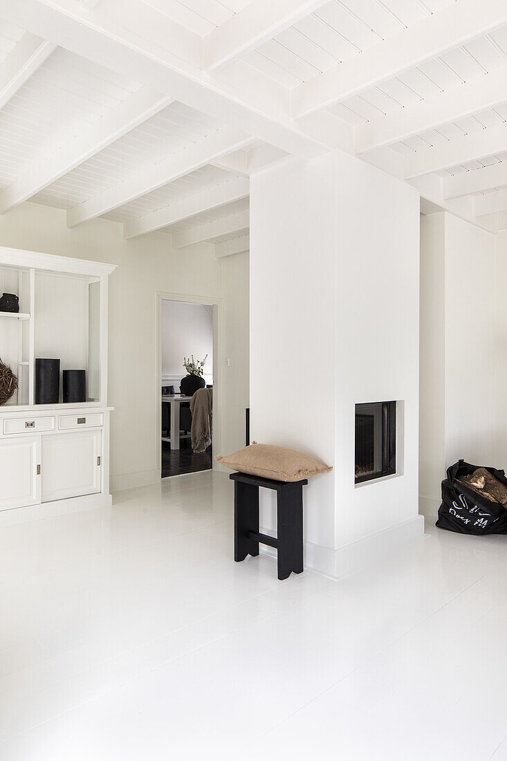 Living room in white with fireplace and wooden beamed ceiling