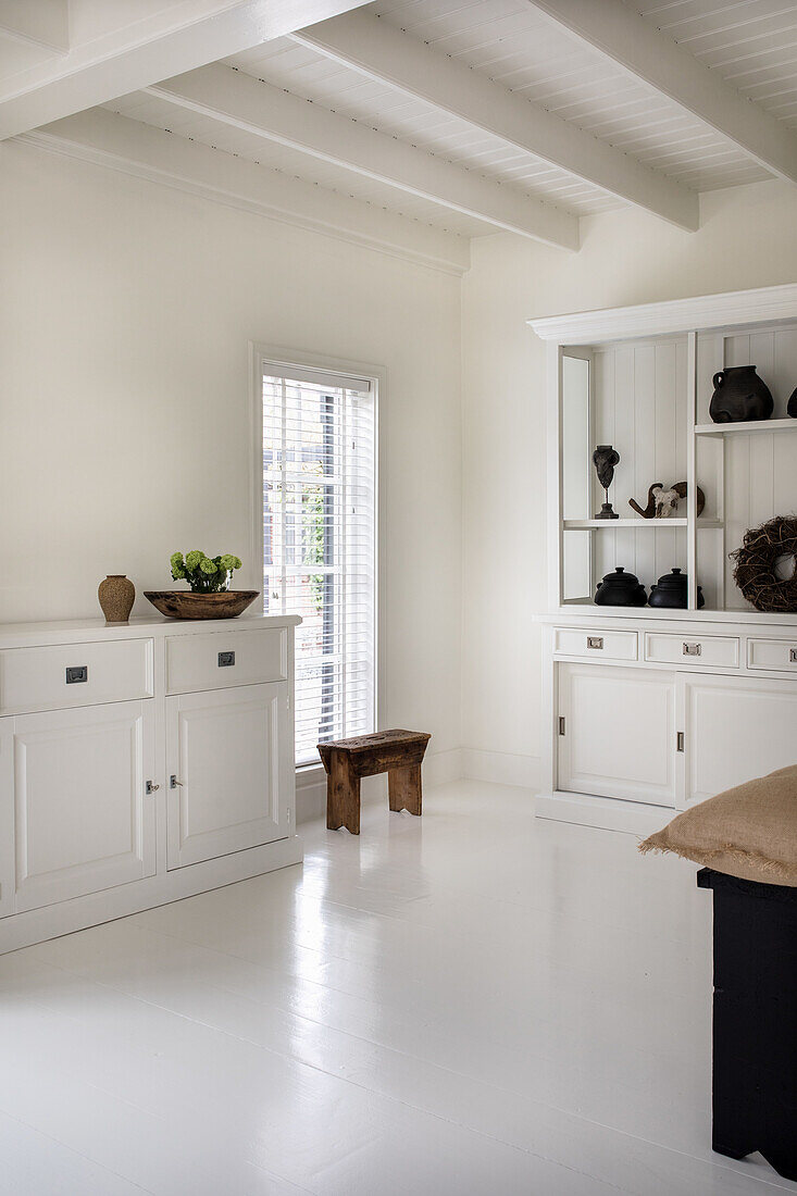 Room with white wooden furniture and white-painted wooden beamed ceiling