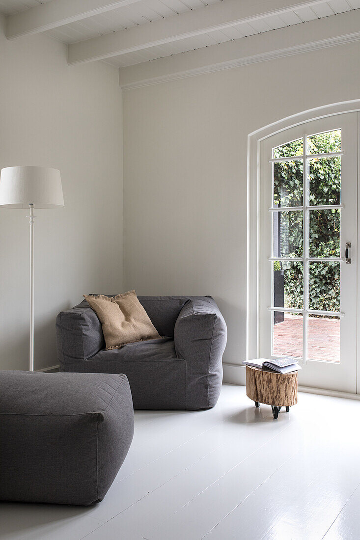 Minimalistisches Wohnzimmer mit grauem Sessel und Blick auf Terrasse