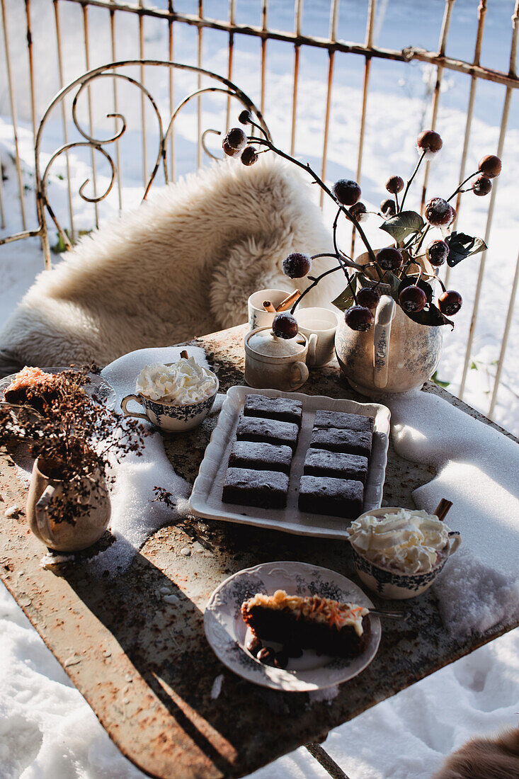 Winter coffee party in the snowy garden with treats