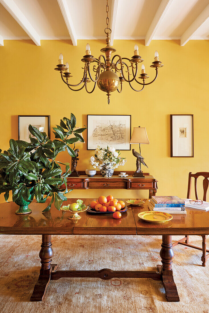 Old-fashioned dining room with solid wooden table, chandelier and yellow wall