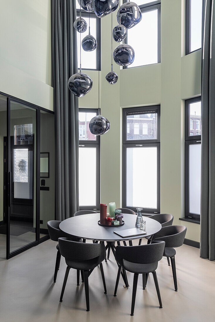 Round dining table with black chairs and spherical pendant light in modern dining area