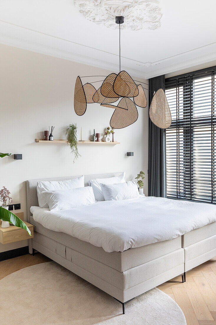 Modern bedroom with beige-colored double bed and decorative pendant light