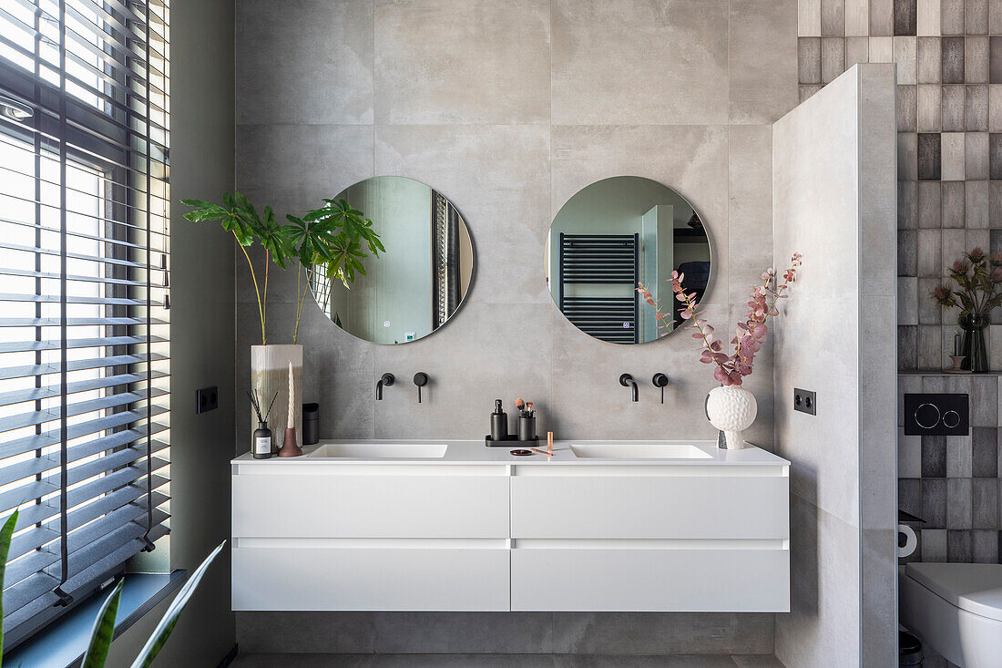 Modern bathroom with double sinks, round mirrors and partition wall