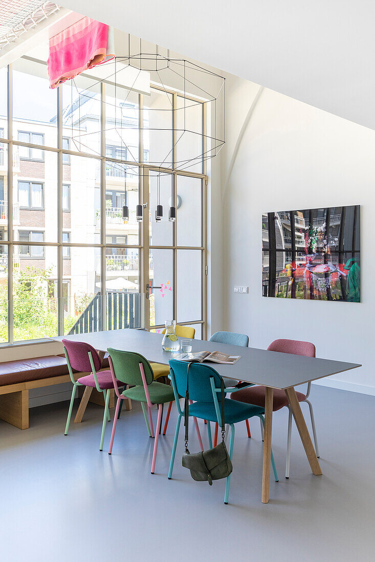 Esszimmer mit bunten Stühlen und großem Fenster im modernen Stil