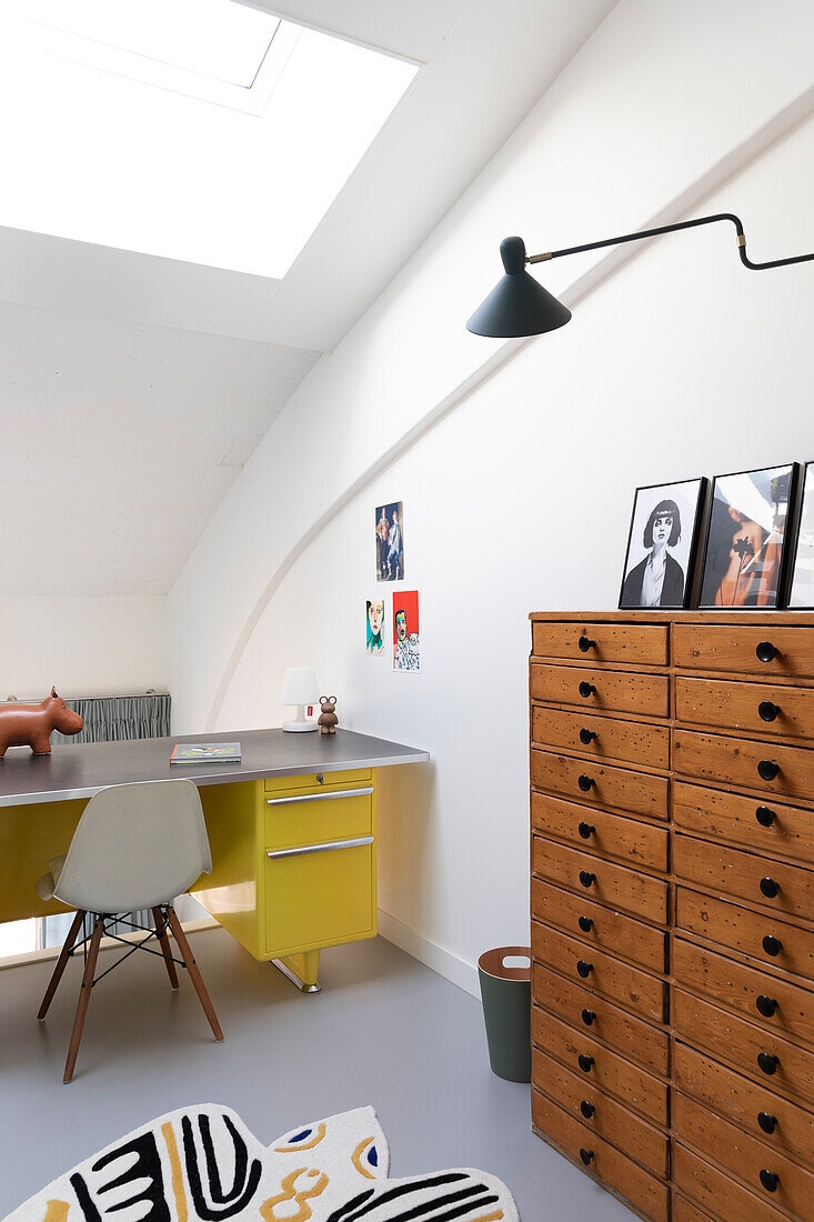 Work area in the attic with chest of drawers and desk, modern furnishings