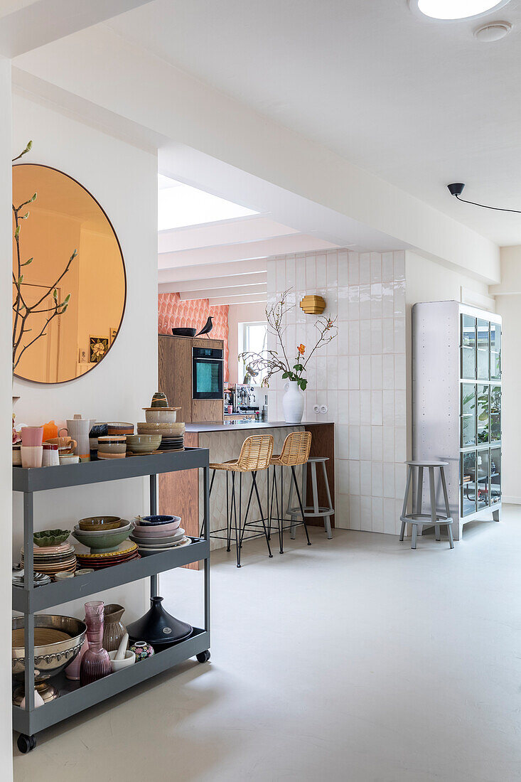 Modern eat-in kitchen with bar counter and shelf with ceramic crockery