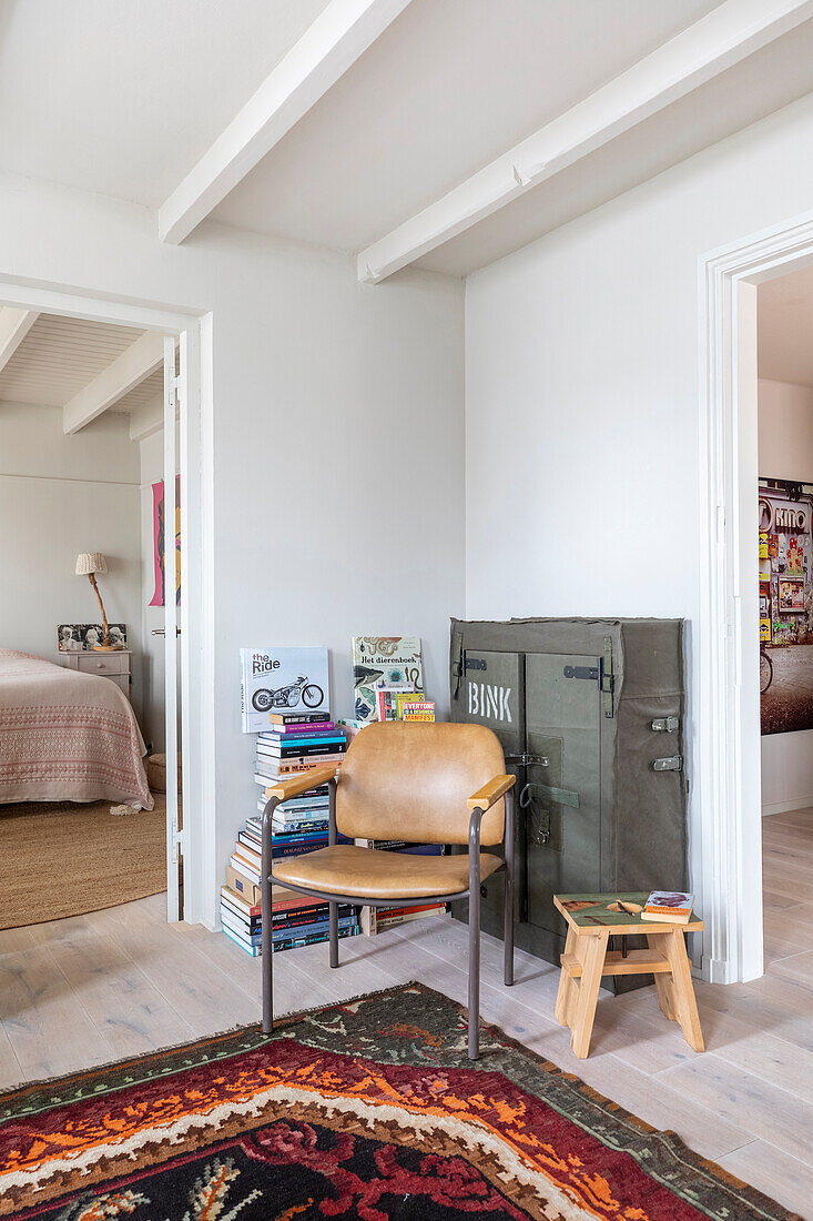 Reading corner with leather armchair and stack of books in bright living area