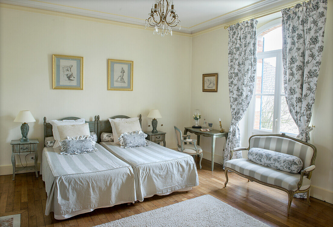 Helles, elegantes Schlafzimmer im französischen Landhausstil mit zwei Einzelbetten und Polsterbank