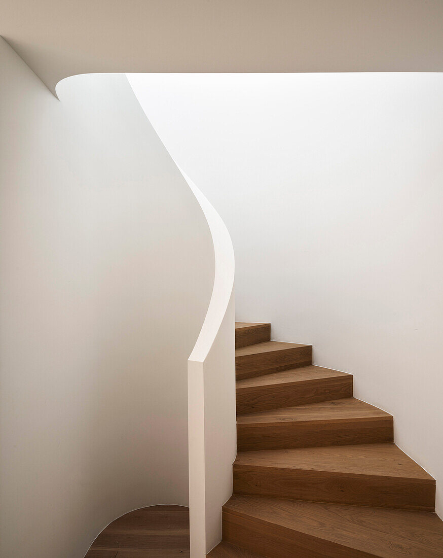 Staircase with wooden steps and white walls