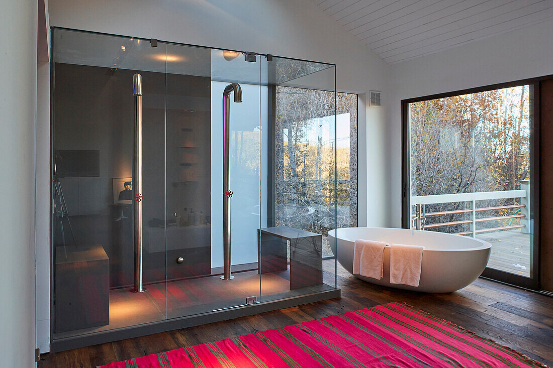 Double shower, bath tub and large window looking out to the deck