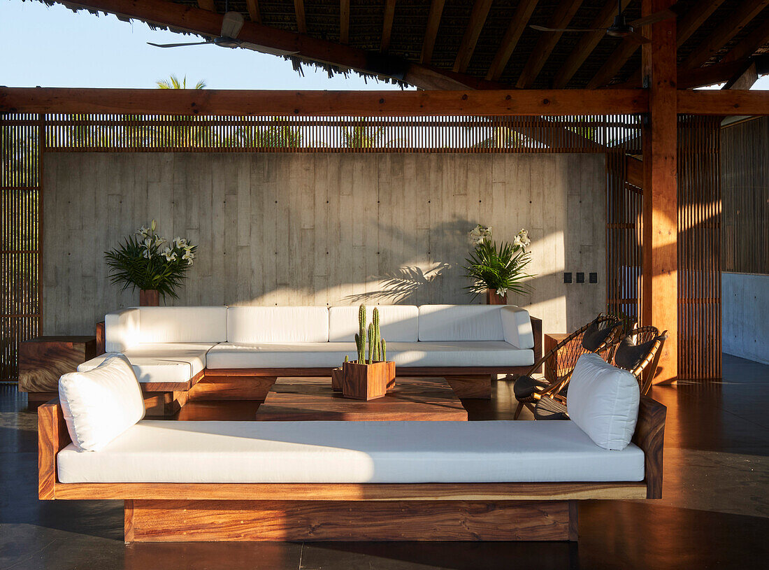 Lounge mit Holzmöbeln und weißen Auflagen im Strandhaus