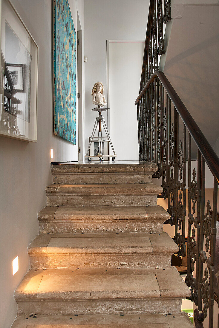 View over stone staircase to landing with artwork and bust