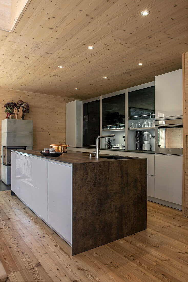 Modern, wood-paneled kitchen with kitchen island and integrated ceiling lighting