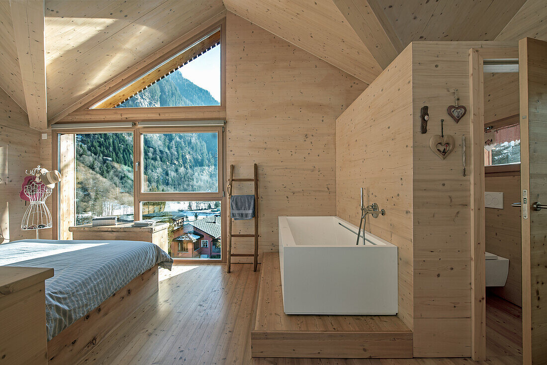 Chalet-style bedroom with free-standing, angular bathtub and panoramic views of the mountains