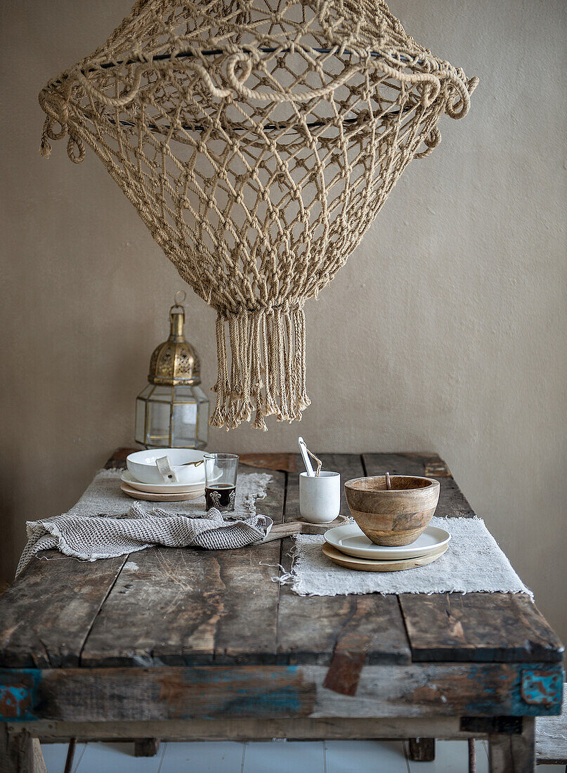 Rustic wooden table with crockery and macramé lamp