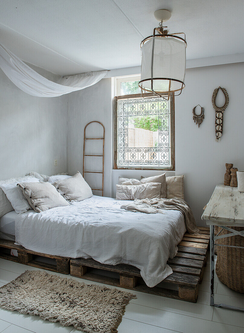 Schlafzimmer mit Palettenbett, Fellteppich und rustikalen Dekorationselementen