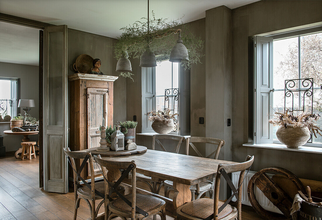 Dining room with rustic wooden table and chairs, wooden cupboard and window decorations