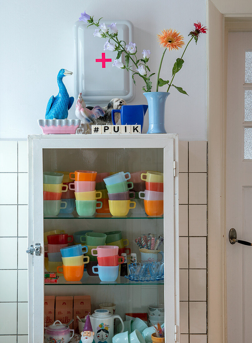 Vitrinenschrank mit bunten Tassen und Vasen in der Küche