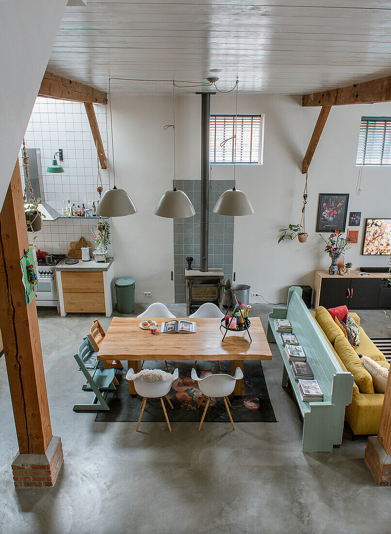 Open-plan living and dining area with wooden table, bench and wood-burning stove