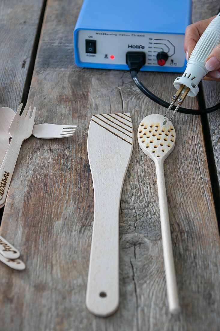 Wooden spoon with branding pattern and branding tool on rustic wooden table