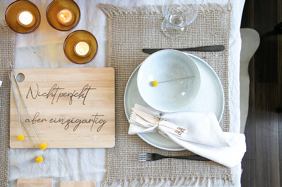 Set dining table with message on wooden board and candle lights