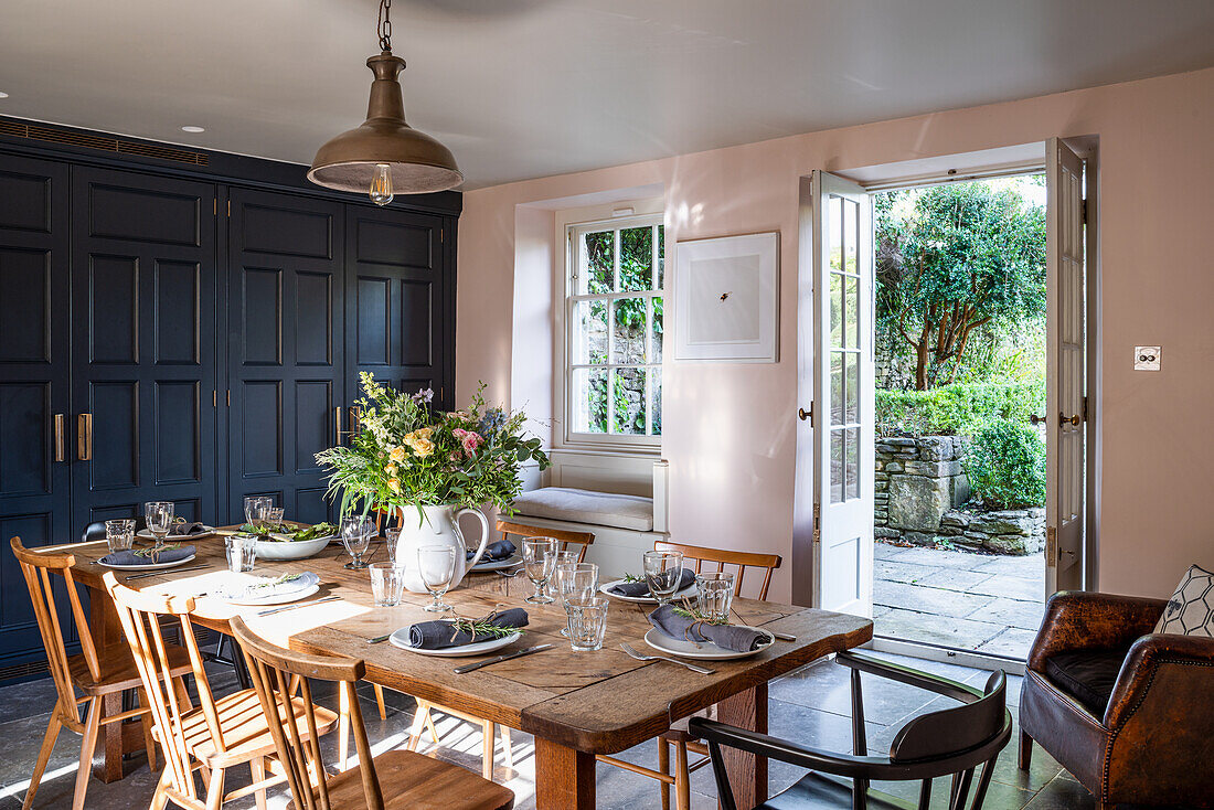 Dining room with rustic wooden table, flower vase and open access to the terrace