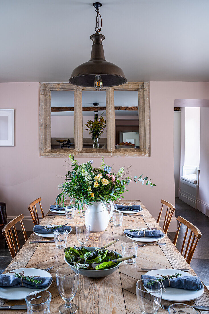 Set wooden table in the dining room with flower arrangement and pendant light