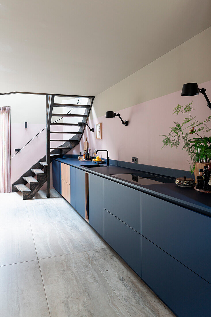 Modern kitchen with blue base units and staircase in the background