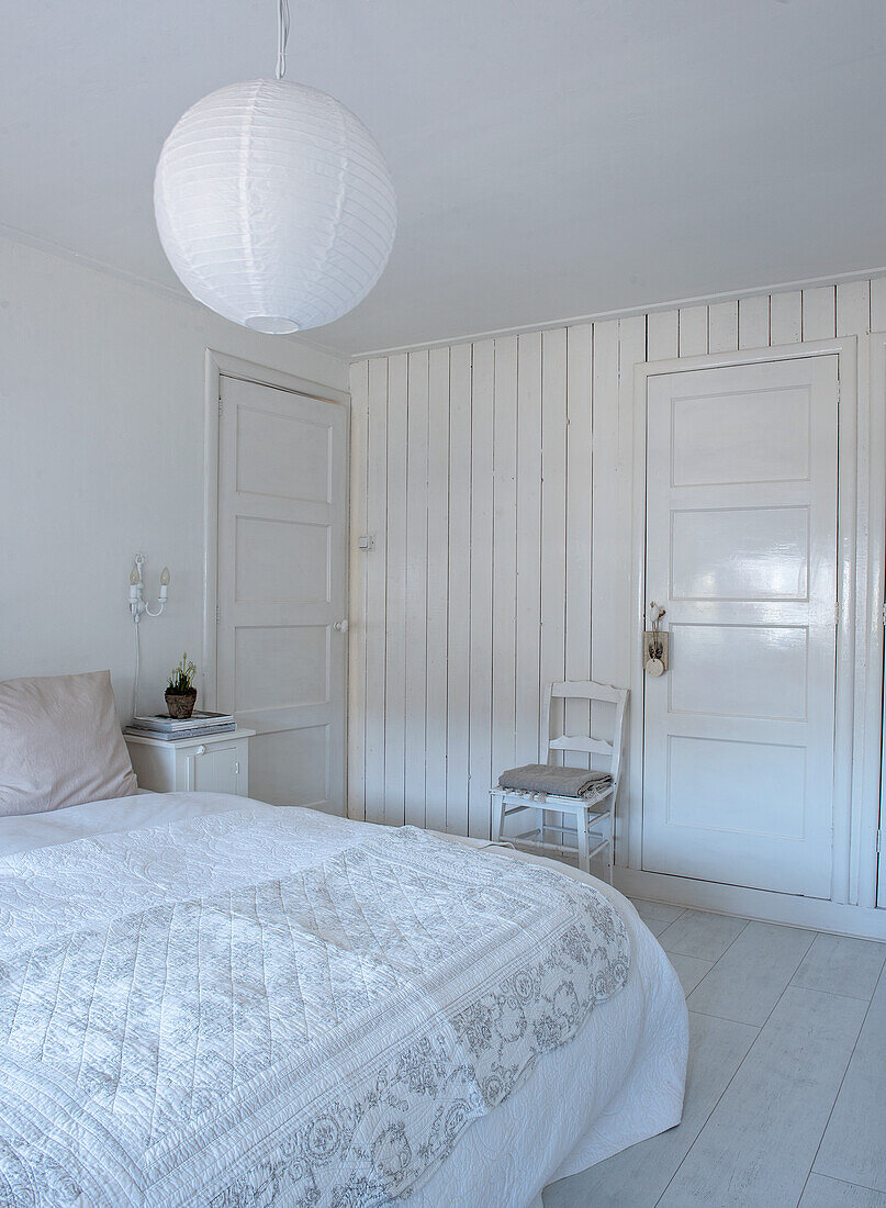 Schlafzimmer in Weiß mit Holzwand und Papierlampe